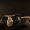 Group view of several Rind Marble Tables in different shades arranged on dark floor with spotlighting