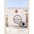 Aerial shot of a white brick wall with 'OIL DIESEL ADDITIVES' signage, an Indian head graphic, and stacked tires in desert...