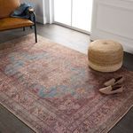 Styled room scene with the medallion rug on wood floor alongside tan leather chair, woven pouf, and shoes