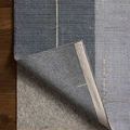 Folded corner showing underside of rug and natural fiber rug pad beneath