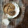 Plaid throw draped over table with holiday cookies on a plate and a glass of milk nearby