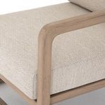 Detail of light wood frame armrest curvature and beige cushioned seat corner
