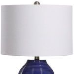 Close-up of white linen drum lamp shade with brushed nickel finial and frame details