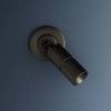 Wall sconce illuminated against dark blue wall displaying matte distressed bronze finish and directional arm