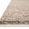 Low angle close-up showing braided dark border and rug’s flat textured pile