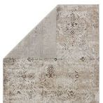 Backside of rug partially folded to reveal reverse pattern in muted gray tones