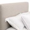 Close-up of textured fabric upholstery on tall, rectangular headboard with pillows.
