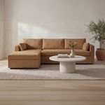 Frida outdoor coffee table styled on a light rug in front of a tan sectional sofa with neutral decor and a potted plant ne...