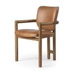 Three-quarter angle showing chair’s armrest curve, wood grain, and caramel leather cushions