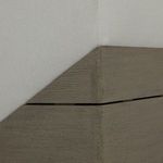 Close-up detail on chair corner showing seam between fabric upholstery and wood base