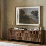 Artwork hung above a wooden console table with decor items on a textured beige wall