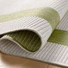 Rug slightly rolled up on hardwood floor revealing reversible design and texture