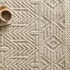 Top-down view of Noelle Ivory / Black Rug corner with book and cup on textured surface and fringe