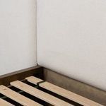 Corner detail showing contrast between plush fabric headboard and natural wood finish of frame