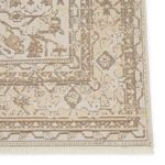 Close-up of rug corner highlighting intricate geometric border and soft distressed botanical motifs.