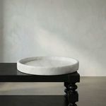 Marble tray displayed on a black wooden table with turned legs against a pale textured wall
