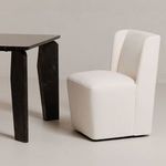Cream chair positioned beside dark wood table in minimalist room setting