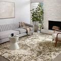 Spirit Pewter Olive rug styled in bright living room with gray sofa, white side table, and stone fireplace
