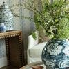 Barclay Butera vase on glass coffee table filled with lush green and white flowers in cozy living room