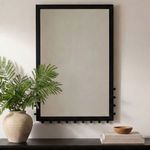 Figaro wall mirror mounted on wall above black surface next to a potted fern and decorative items