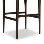 Close-up on dark stained wooden legs and the horizontal footrest bars of the stool frame