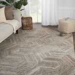 Rug styled in living room with light-filled window, beige sofa, knit pouf, and wooden side table