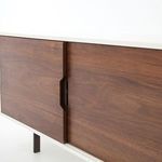 Close-up of sliding walnut doors with carved recessed handles along white frame