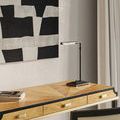 Desk lamp styled on light wood desk beneath black and white abstract artwork