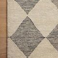 Folded rug showing thickness and dense wool pile in beige and charcoal diamond pattern