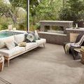 Outdoor patio setting featuring the rug under a modern seating arrangement near a pool and fireplace.