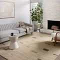 Bowery Slate taupe rug in minimal light-filled living room with gray sofa, fireplace, and plant