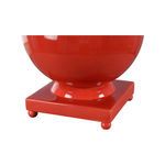 Close-up view of red ceramic ball lamp's square base with rounded feet and glossy finish