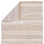 Back side of rug with folded corner revealing woven backing in muted tones