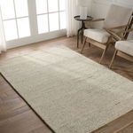 Rug styled in bright room with light wood flooring, positioned under two cream cushioned wooden armchairs