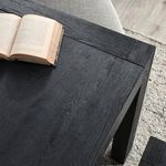 Top close-up showing the black wood grain of table surface with an open book placed on it