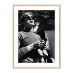 Black and white framed photograph of Andy Warhol holding a bunch of bananas wearing sunglasses