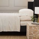 Full side view of bamboo linen pillowcases styled on pillows stacked on black bed frame with woven lamp and textured night...