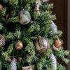 Two owls featured separately on a Christmas tree with gold and bronze round and cone ornaments