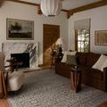 Milena Denim Natural Rug styled in living room with brown sofa, armchair, wood details, and fireplace