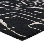 Angled close-up of rug edge highlighting hand-tufted stitching and soft wool material textures.