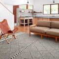 Sawyer Black Rug in modern living room with wood floor, tan sofa, and leather chair
