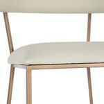 Close-up of cushioned white faux leather seat and brass-finished metal frame