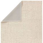 Backside view revealing solid light gray backing and folded corner of taupe and cream striped rug