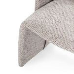 Close-up of chair’s left leg and seat junction showing woven beige fabric texture and stitching
