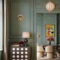Polyhedron Small Pendant hanging in green walled room above dining table with beige chairs