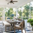 Bench styled on porch dining set with wicker chairs, blue-striped rug, and greenery through screened patio