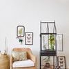 Chair styled next to clear glass terrarium with greenery and hanging plant macrame holder