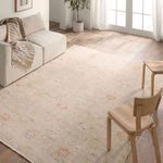 Rug styled in a bright room with wooden floor, cream sofa, and wooden chairs