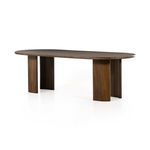 Oval dining table in caramel Guanacaste wood with tonal curved tabletop and arched legs showcasing expressive grain.