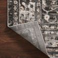 Folded back corner of Estelle rug revealing grey woven backing beneath pile